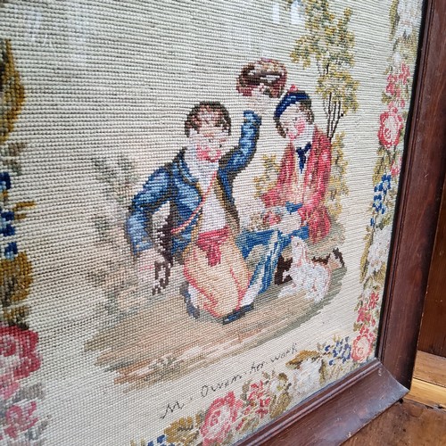 23 - A Victorian woolwork tapestry, embroidered with two Scottish boys and a dog, meandering floral borde... 