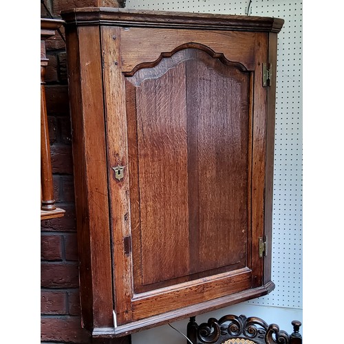 29 - A George III oak splay front corner cabinet, shaped fielded panelled door, 98cm high, 79cm wide, c.1... 