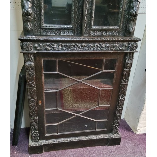 45 - A tall Victorian ebonised display cabinet, comprising of heavily carved with masks, scrolls and flow... 