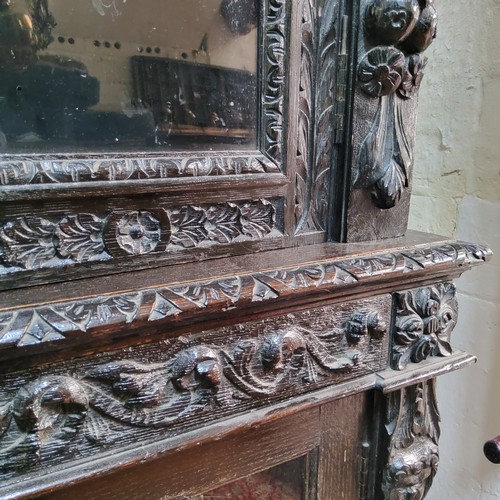 45 - A tall Victorian ebonised display cabinet, comprising of heavily carved with masks, scrolls and flow... 