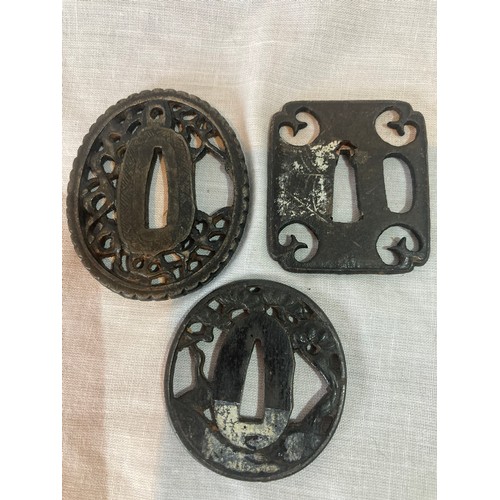 251 - A Japanese iron tsuba, oval, pierced with blossoming prunus, 4.5cm wide;  others (3)