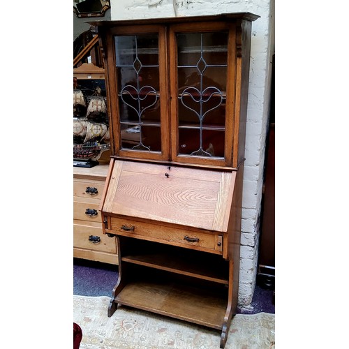 474 - An Arts & Crafts oak bureau bookcase with oversailing cornice, sinuous stained glass leaded pane... 