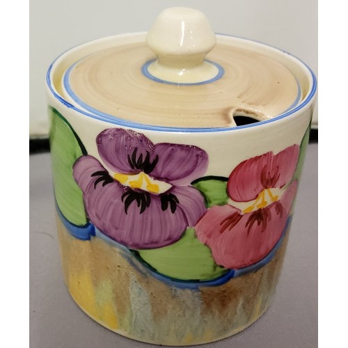 172 - A Clarice Cliff Pansy pattern cylindrical preserve pot and cover, painted with pansies above a dripp... 