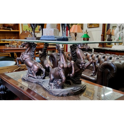 600 - A decorative bronzed resin and toughened glass coffee table raised on rampant Marley horse supports ... 