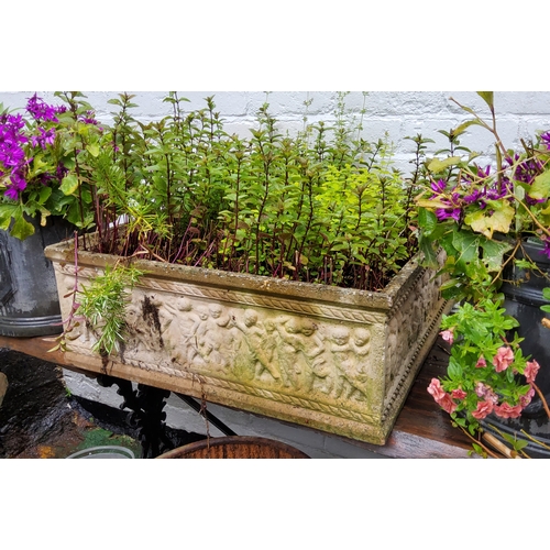 763 - A large square reconstituted stone planter, decorated in relief with putti figures, with herbs