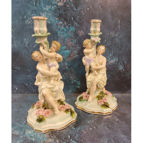 16 - A pair of German figural candlesticks, of a maiden and cherub, floral encrusted bases, 31cm high, c.... 