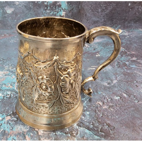 129 - A George III silver spreading cylindrical mug, embossed with stylised flowers and leaves, 9cm high, ... 