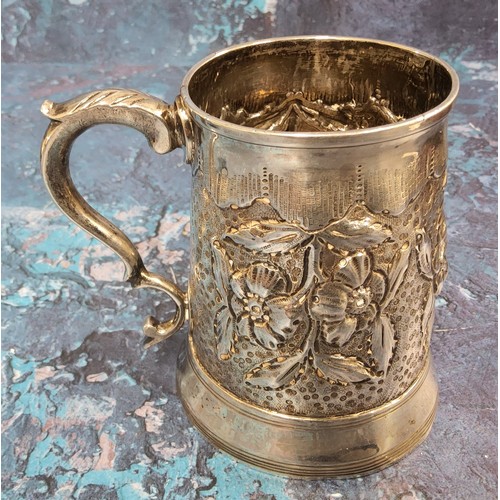 129 - A George III silver spreading cylindrical mug, embossed with stylised flowers and leaves, 9cm high, ... 