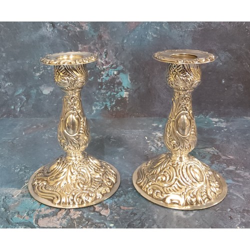 141 - A pair of Victorian style silver boudoir candlesticks, embossed overall with foliage and scrolls, 12... 