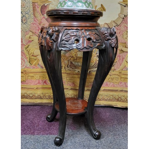 392 - A 19th century Chinese hardwood jardiniere / temple vase stand, carved with oriental iris flower hea... 