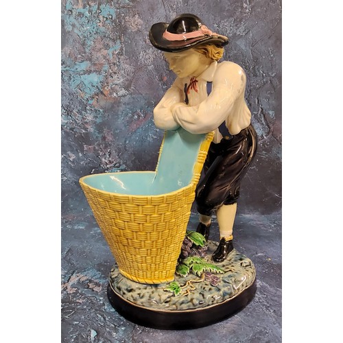 349 - A Minton majolica figure, The Grape Picker, he stands leaning on his pannier, 24cm high, impressed m... 