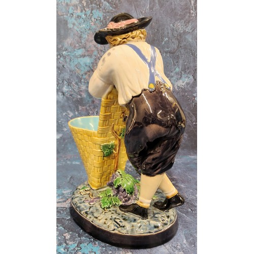 349 - A Minton majolica figure, The Grape Picker, he stands leaning on his pannier, 24cm high, impressed m... 