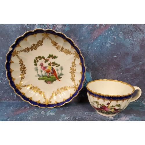 293 - A Worcester fluted teacup and saucer, painted with fanciful birds standing and in flights, blue band... 