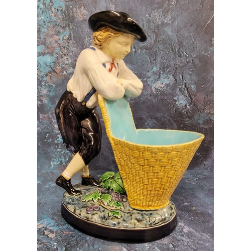 16 - A Minton majolica figure, The Grape Picker, he stands leaning on his pannier, 24cm high, impressed m... 