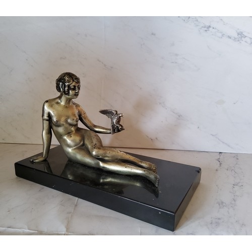 51 - Art Deco, a silvered bronze, a lady with a bird, reclining, black rectangular marble base, 22cm wide