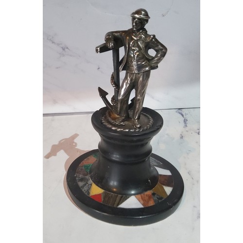 103 - A silver coloured metal figure, of a sailor standing by an oversized anchor, pietra dura capstan bas... 