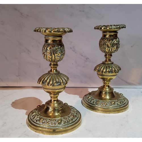 119 - A pair of post Regency bronze candlesticks, the sconces cast with floral border, knopped stems, spre... 