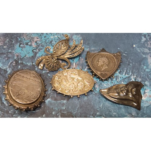 261 - Vintage brooches including an unusual white metal shield shaped brooch/stand, holding a George IV sh... 