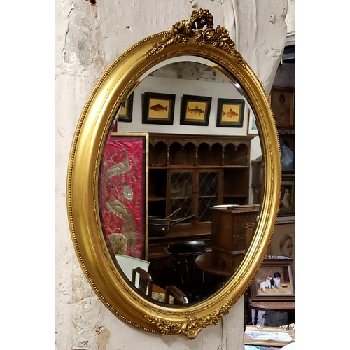 620 - A Victorian oval parcel gilt mirror surmounted with floral swags, bevelled edge looking glass 67cm h... 