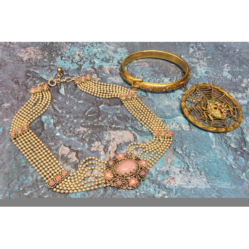 256 - A white metal seven string choker, centering on a plaque set with a central pink oval stone; a gold ... 