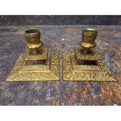 577 - A pair of 19th century brass low candlesticks, leafy sconces, square drip plates, spreading square b... 