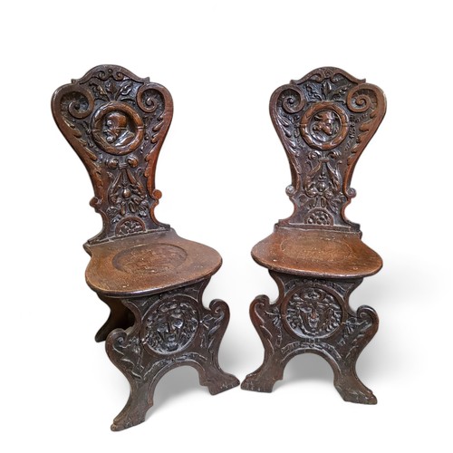 655 - An unusual pair of '17th Century' Continental sgabello hall chairs, the back profusely carved with s... 