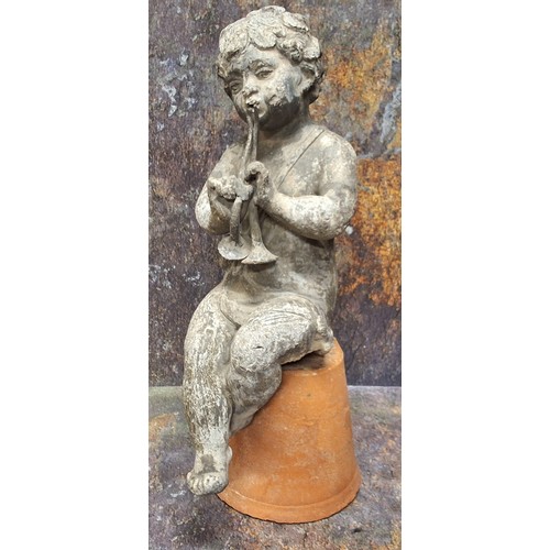 736 - A 19th century lead garden figure, of a scantily clad cherub playing Pan pipes, seated on a upturned... 