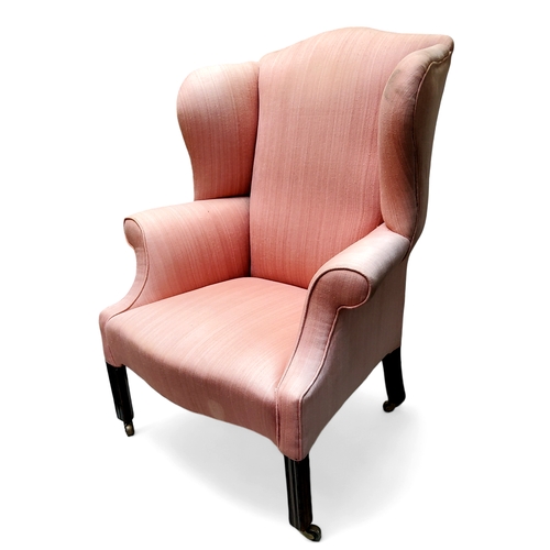 750 - A George III mahogany wingback armchair, pinstriped pink upholstery, fluted stile legs, brass castor... 