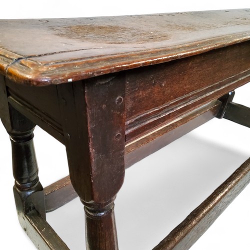 763 - An early 17th century Charles I English oak bench or long joint stool, moulded top above a deep flut... 