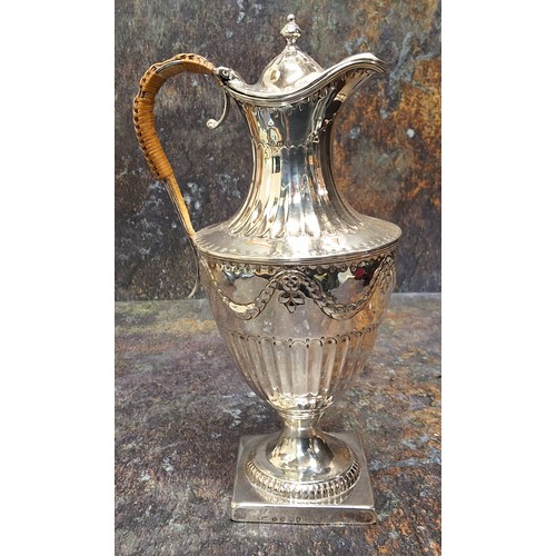 61 - A George III silver urnular hot water pot and cover, half fluted below ribbon tied swags, domed cove... 