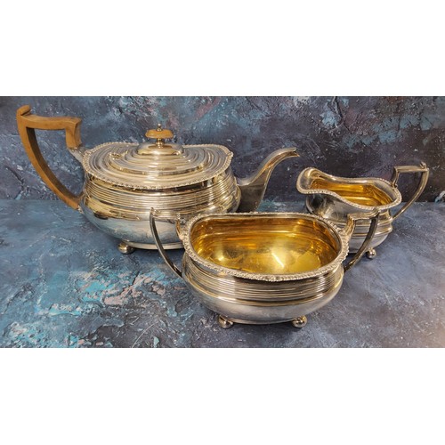 64 - A silver composed three-piece boat shaped tea service, reeded band, gadrooned border, ball feet, 16c... 