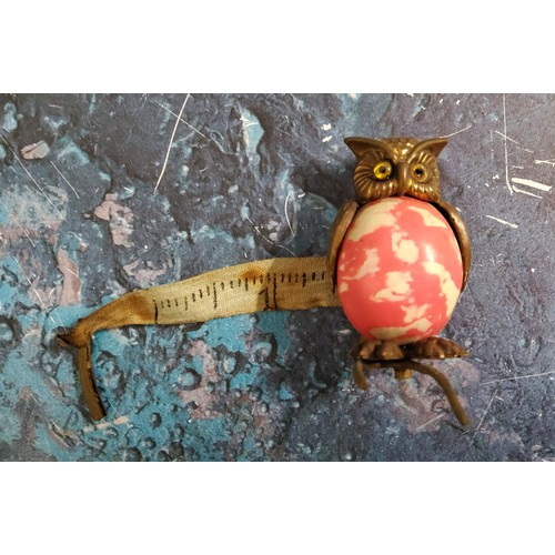 154 - An Edwardian novelty tape measure, as an owl, 'marbled' pink body, 4.25cm high, c.1910