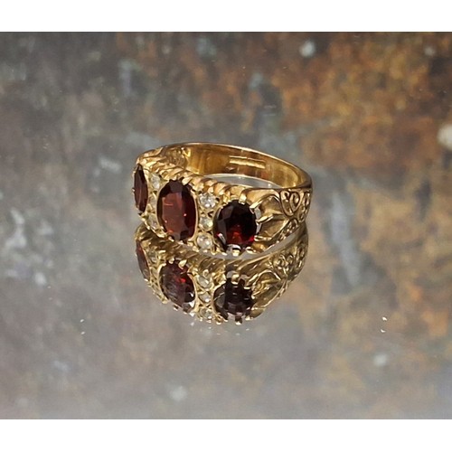 93 - A 9ct gold, garnet and diamond gypsy ring, centrally set oval garnet flanked by a further two, inter... 