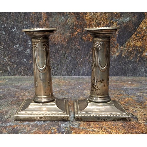 20A - A pair of silver candlesticks, detachable nozzles, beaded borders, the columns in relief with ribbon... 