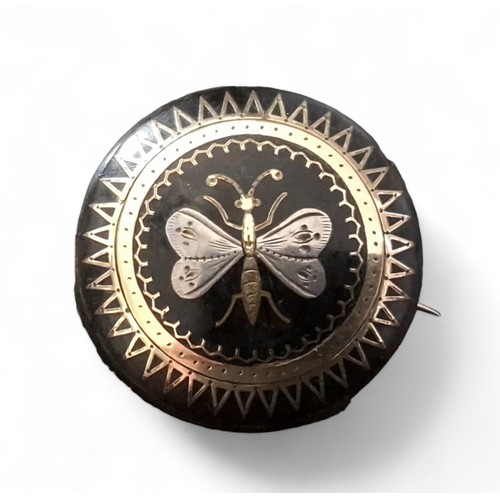 238 - A Victorian circular tortoiseshell pique ware brooch decorated with a butterfly, 32mm dia.