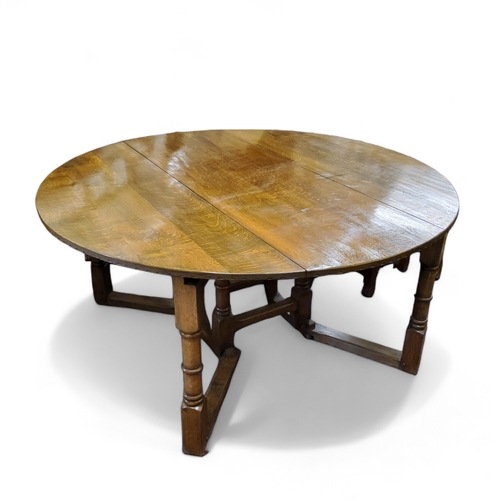 223 - Nigel Griffiths - a 20th century golden oak drop leaf gateleg circular table, made by Nigel Griffith... 