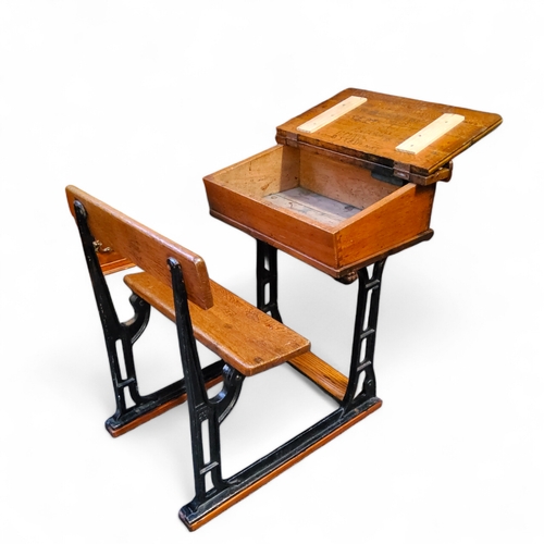 471 - An early 20th century elm and cast iron child's school desk, heavily graffitied hinged cover, 77cm x... 