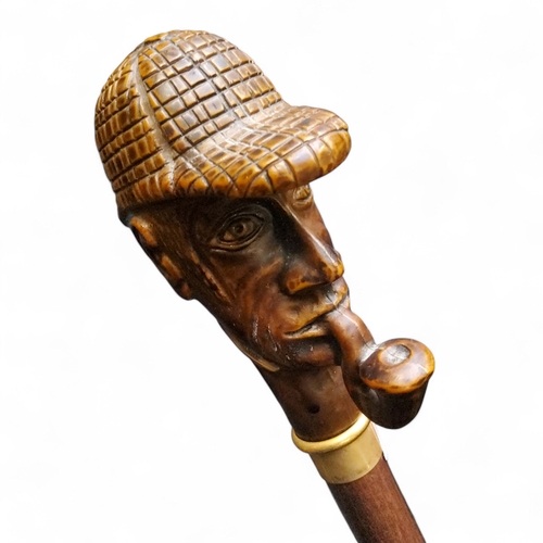 482 - A novelty walking cane terminating with Sherlock Holmes pommel, brass collar, 91cm high