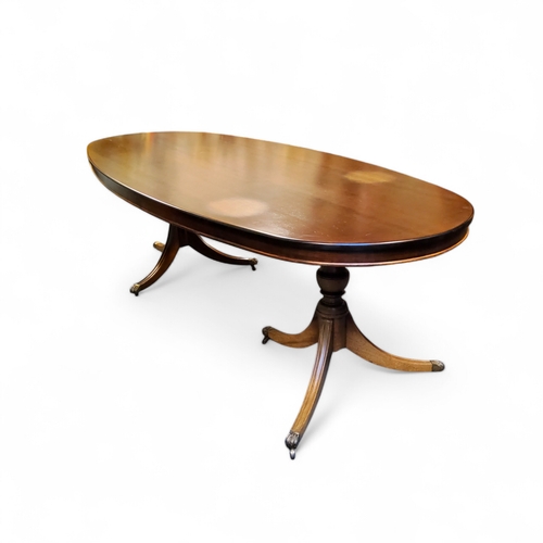 552 - A large reproduction oval dining table, turned urnular columns with outswept fluted legs terminating... 