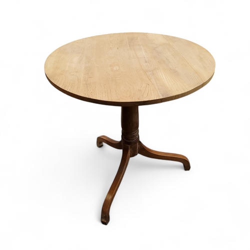 386 - An early 19th century bleached elm circular tilt top farmhouse table, turned support, cabriole legs,... 