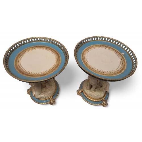 81 - A pair of mid 19th century Minton figural comports, the pierced circular dishes, banded in turquoise... 