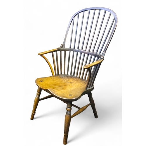 438 - An early 19th century ash and elm Windsor elbow chair with a high hoop back, bowed mid rail, concave... 