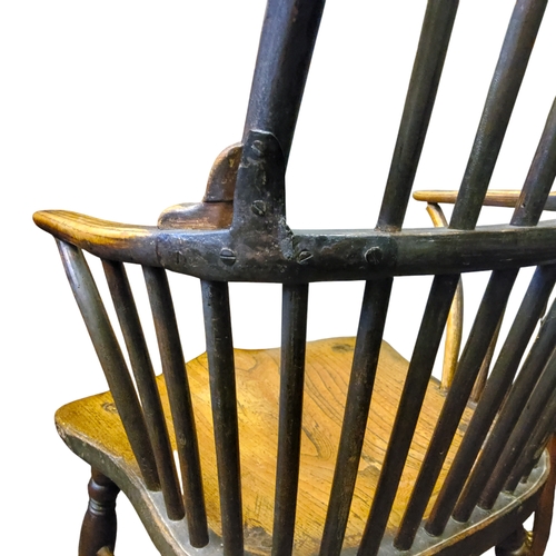 438 - An early 19th century ash and elm Windsor elbow chair with a high hoop back, bowed mid rail, concave... 