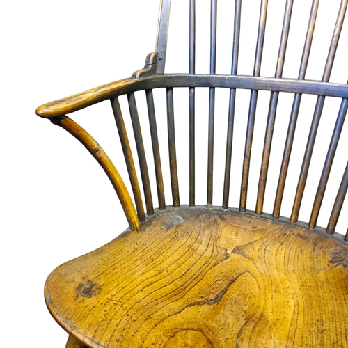 438 - An early 19th century ash and elm Windsor elbow chair with a high hoop back, bowed mid rail, concave... 