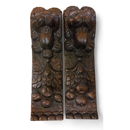 355 - A pair of 18th century oak pilasters, carved with lion heads, fruit and acanthus, 38cm long