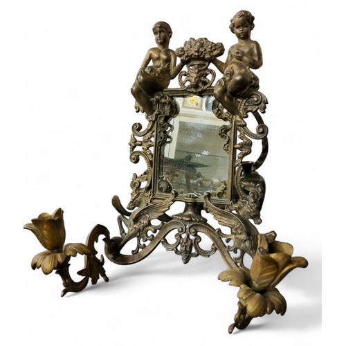 446 - An early 20th century brass looking glass, surmounted with scantily clad figures flanking flowers, t... 