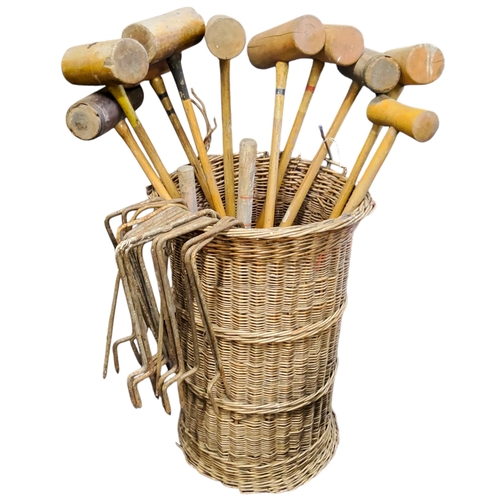 573 - Nine various early 20th century lawn croquet mallets and iron hoops housed in a cylindrical woven wi... 