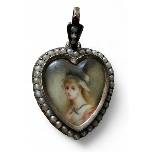 31 - A Victorian gold and seed pearl heart shaped pendant, set with portrait of a young lady wearing a bo... 