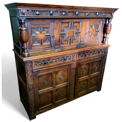 622 - An English oak court cupboard, the upper section with a dental frieze above two block fronted cupboa... 