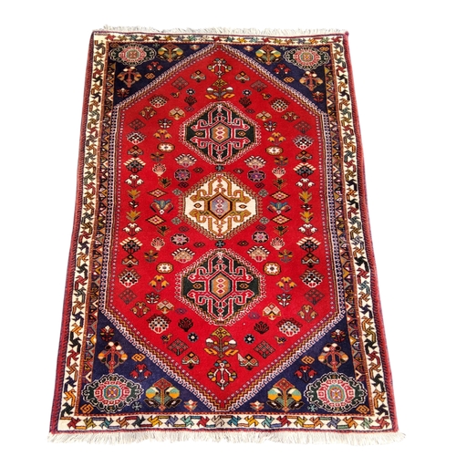 700 - An Oriental Qashgai rug, vivid tones of red and blue, three central guls, 159cm x 109cm